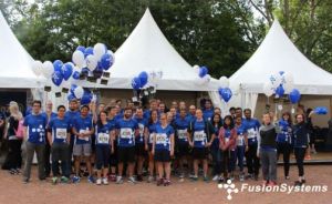 Gruppenfoto der FusionSystems-LÃ¤ufer mit ihren Startnummern vor Pavillons mit Luftballons